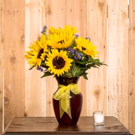 Sunflower bouquet in a dark vase with a yellow ribbon