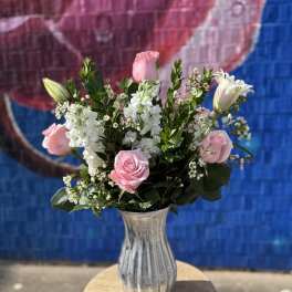 Pink roses and white flowers arranged in a silver vase