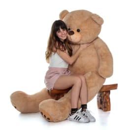 Woman hugging a giant teddy bear on a wooden bench