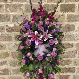 Standing floral spray with pink roses and lilies on a white easel
