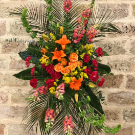 Tall floral standing spray with orange lilies, roses, and pink snapdragons