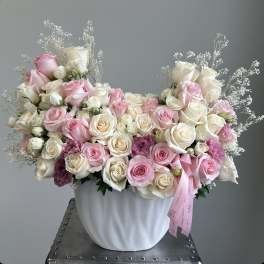 Pink and white rose arrangement in a white vase