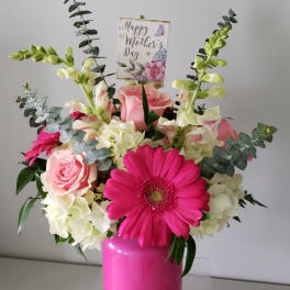 Pink and white floral arrangement in a bright pink vase with a Mother’s Day card