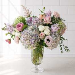 Pastel bouquet of hydrangeas, roses, and anemones in a clear glass vase
