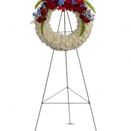 Standing funeral wreath with red, white, and blue flowers on an easel