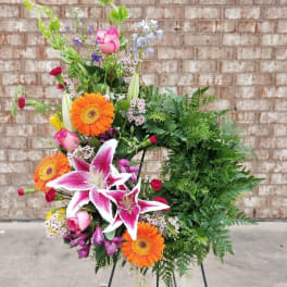 Colorful floral wreath with lilies, gerberas, and roses on a stand