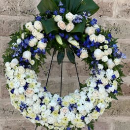 Large white and blue floral wreath on a stand