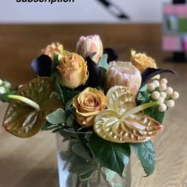 Arrangement of peach roses and anthuriums in a clear glass vase