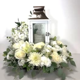 White floral arrangement around a white lantern with a candle inside