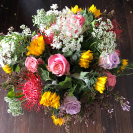 Mixed bouquet with pink and lavender roses, yellow blooms, and white filler flowers