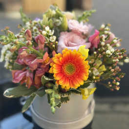 Mixed bouquet with a bright orange gerbera daisy in a white hatbox