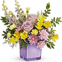 Lavender and yellow mixed flower arrangement in a purple glass vase
