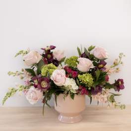 Pink and purple flower arrangement in a blush pedestal vase