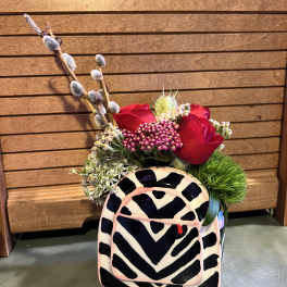 Red roses in a patterned ceramic container with pussy willow branches