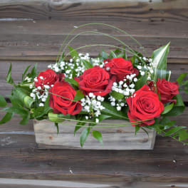Red roses arranged in a rectangular wooden box with white filler flowers