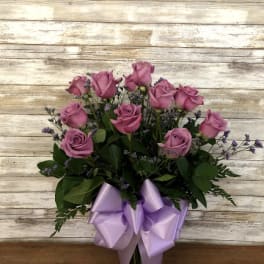 Pink roses in a glass vase with a lavender ribbon