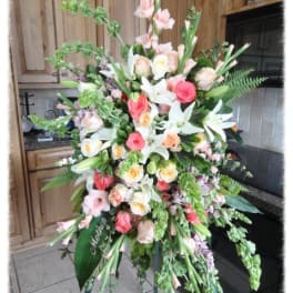 Large standing floral spray with pink, white, and peach blooms