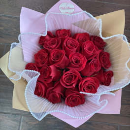 Bouquet of red roses wrapped in pink and beige paper with white tulle