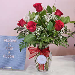 Red roses in a glass vase with a red ribbon