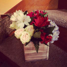 Mixed bouquet of white, red, and pale pink flowers in a wooden box