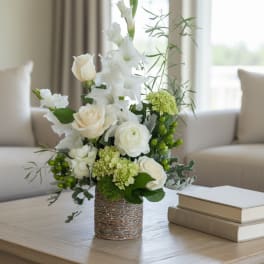 White roses and lilies arranged in a woven vase on a table