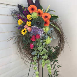 Colorful floral wreath on a stand with orange, purple, yellow, and pink blooms