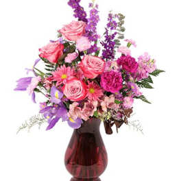 Pink and purple mixed flower arrangement in a red glass vase