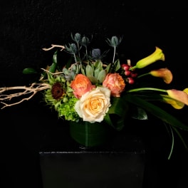 Arrangement of peach roses and yellow calla lilies in a dark vase