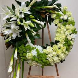 Floral wreath with white lilies, cream roses, and green pom-pom blooms