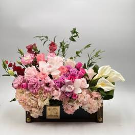 Pink and white floral arrangement in a dark wooden box