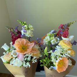Two mixed bouquets with pastel poppies, snapdragons, and daisies in kraft wrap