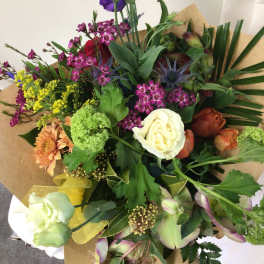 Mixed bouquet with roses, orchids, and other flowers wrapped in brown paper