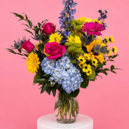 Colorful bouquet of roses, hydrangeas, and daisies in a glass vase