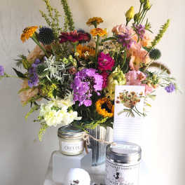 Mixed bouquet in a metal vase with a note card and tea tins in front