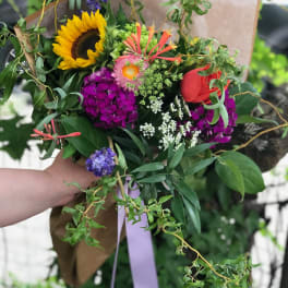 Hand-tied bouquet with a sunflower, red rose, and purple blooms