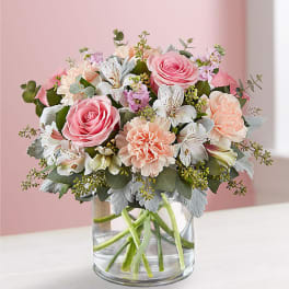Pink roses and peach carnations in a clear glass vase