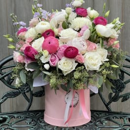 Pink and white mixed flower arrangement in a round pink box