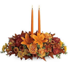 Orange floral centerpiece with two taper candles