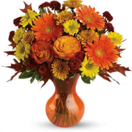 Orange and yellow mixed flower bouquet in an amber vase
