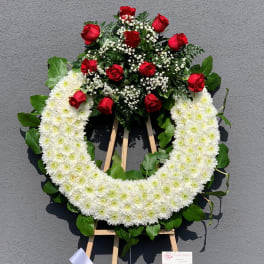 White chrysanthemum wreath with red roses on a standing easel