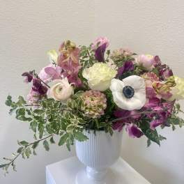 Mixed pink and white flowers arranged in a white pedestal vase