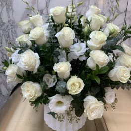 White rose arrangement in a white vase with eucalyptus accents