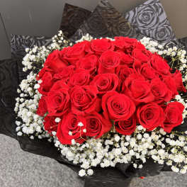 Bouquet of red roses with white baby's breath in black wrap