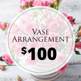 Pink rose arrangement in a vase with a $100 label