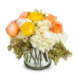 Bouquet of yellow and peach roses with white hydrangeas in a glass vase