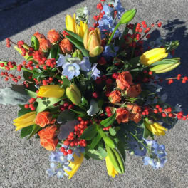 Bouquet of yellow tulips, orange roses, and blue flowers with red berry stems