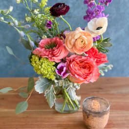 Mixed bouquet in a glass vase with pink, peach, purple, and white blooms