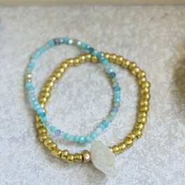 Two beaded bracelets with blue and gold beads and a white shell charm