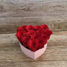 Heart-shaped box of red roses on a wooden surface