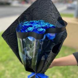 Bouquet of bright blue roses wrapped in black paper